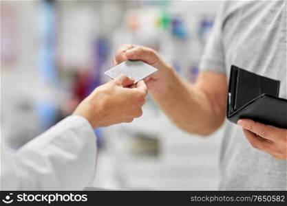 medicine, payment and finance people concept - close up of hand giving bank card to pharmacist. close up of hand giving bank card to pharmacist
