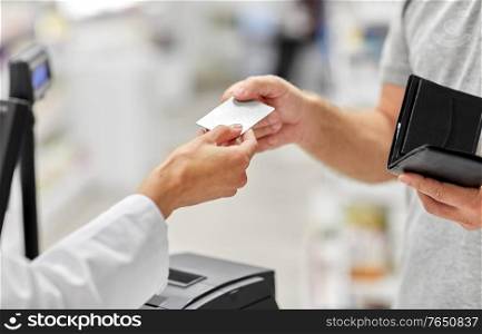 medicine, payment and finance people concept - close up of hand giving bank card to pharmacist. close up of hand giving bank card to pharmacist