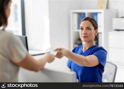 medicine, people and healthcare concept - female doctor or nurse and patient with prescription at hospital. doctor and patient with prescription at hospital