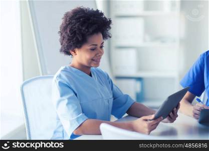 medicine, people and healthcare concept - happy female doctor or nurse with tablet pc computer at hospital