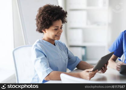 medicine, people and healthcare concept - happy female doctor or nurse with tablet pc computer at hospital