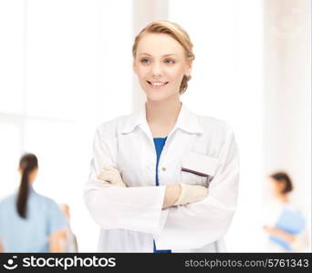 medicine, people, profession and teamwork concept - smiling young female doctor in white coat over group of medics in hospital