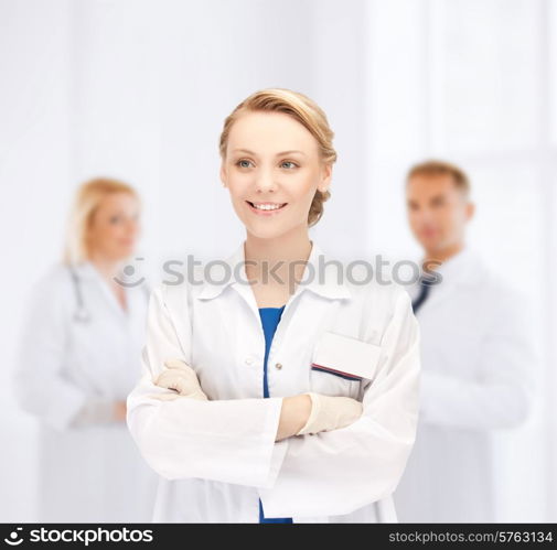 medicine, people, profession and teamwork concept - smiling young female doctor in white coat over group of medics in hospital