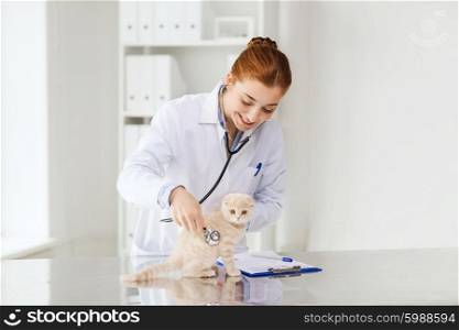 medicine, pet, animals, health care and people concept - happy veterinarian doctor with stethoscope checking scottish fold kitten up at vet clinic