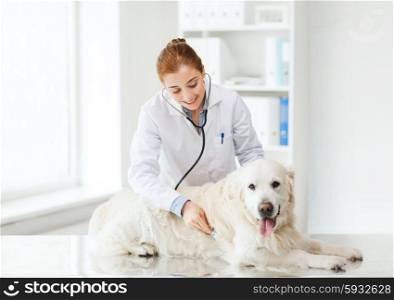 medicine, pet, animals, health care and people concept - happy veterinarian or doctor with stethoscope checking up golden retriever dog at vet clinic