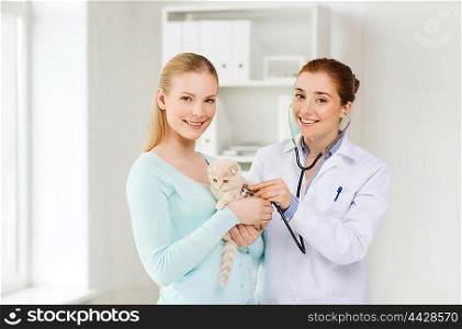 medicine, pet, animals, health care and people concept - happy woman and veterinarian doctor with stethoscope checking scottish fold kitten up at vet clinic