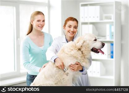 medicine, pet, animals, health care and people concept - happy woman and veterinarian doctor with stethoscope checking up golden retriever dog at vet clinic