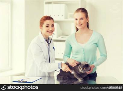 medicine, pet, animals, health care and people concept - happy woman and veterinarian doctor with stethoscope checking british cat up at vet clinic