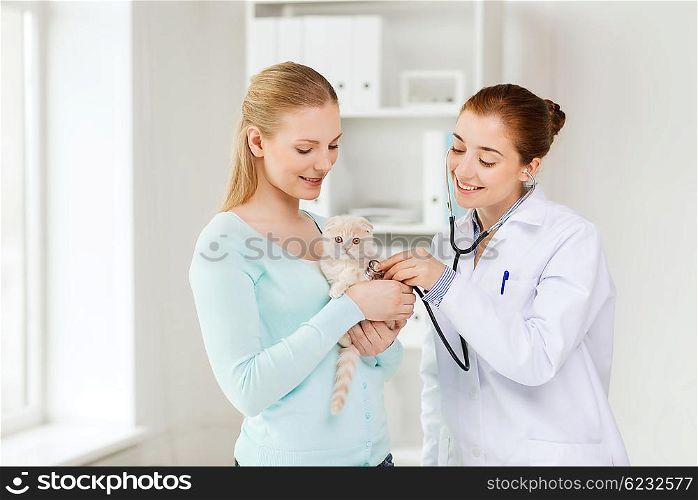 medicine, pet, animals, health care and people concept - happy woman and veterinarian doctor with stethoscope checking scottish fold kitten up at vet clinic