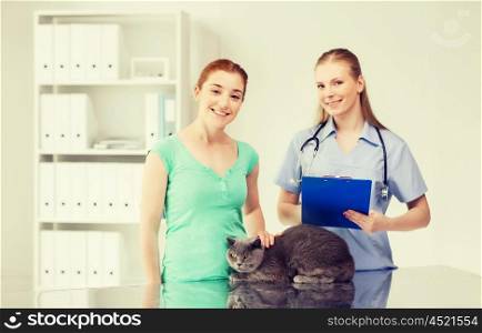 medicine, pet, animals, health care and people concept - happy woman with british cat and veterinarian doctor with clipboard taking notes at vet clinic