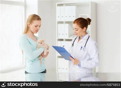 medicine, pet, animals, health care and people concept - woman holding scottish fold kitten and veterinarian doctor with clipboard at vet clinic