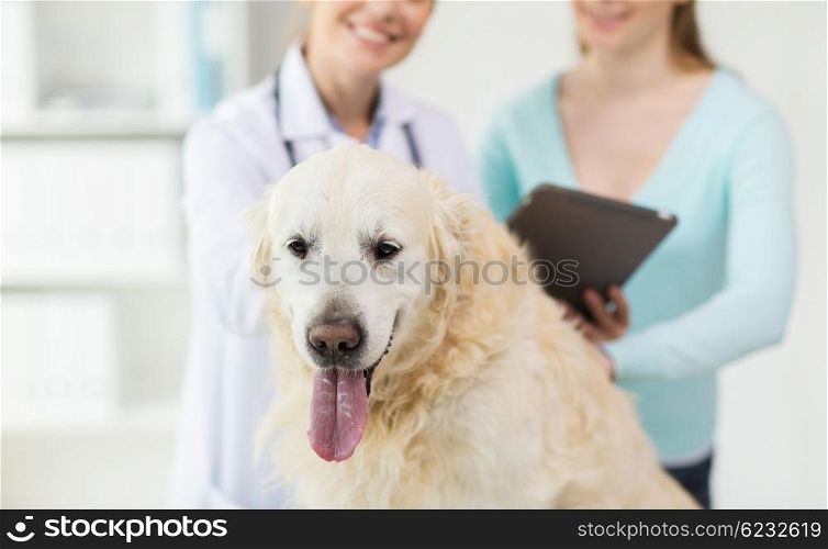 medicine, pet, health care, technology and people concept - close up of happy woman with golden retriever dog and veterinarian doctor holding tablet pc computer at vet clinic