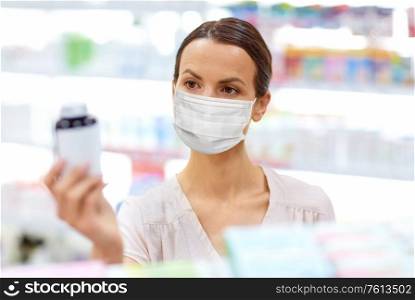medicine, pharmaceutics and healthcare concept - female customer wearing face protective medical mask for protection from virus disease choosing drugs at pharmacy. female customer in mask with medicine at pharmacy