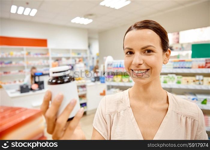 medicine, pharmaceutics, health care and customer concept - happy female customer with drug jar at pharmacy