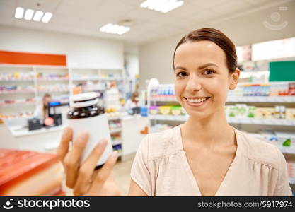 medicine, pharmaceutics, health care and customer concept - happy female customer with drug jar at pharmacy