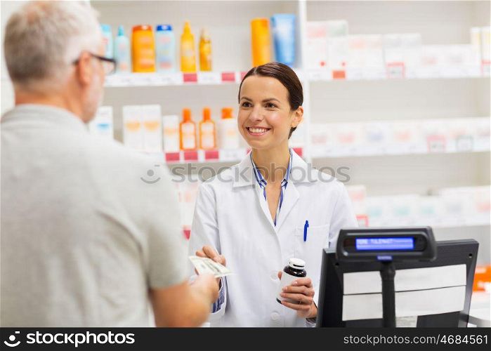 medicine, pharmaceutics, health care and people concept - apothecary and senior man customer buying drug at drugstore. apothecary selling drug to senior man at pharmacy. apothecary selling drug to senior man at pharmacy