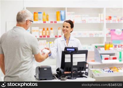 medicine, pharmaceutics, health care and people concept - apothecary and senior man customer buying drug at drugstore. apothecary selling drug to senior man at pharmacy