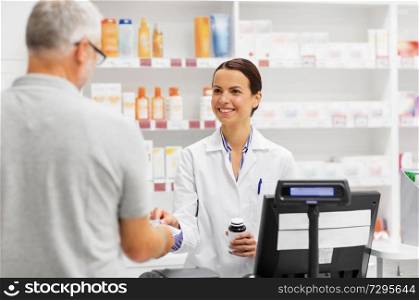 medicine, pharmaceutics, health care and people concept - apothecary and senior man customer buying drug at drugstore. apothecary selling drug to senior man at pharmacy