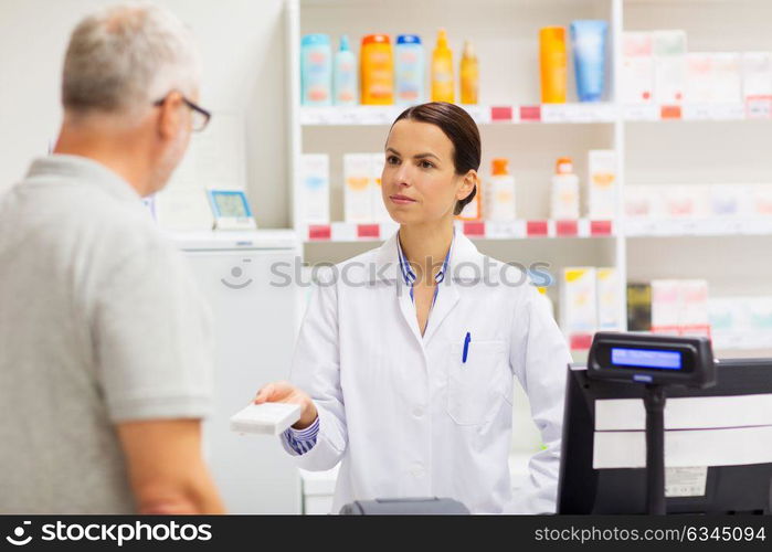 medicine, pharmaceutics, health care and people concept - apothecary giving drug to senior man customer at drugstore. apothecary showing drug to senior man at pharmacy