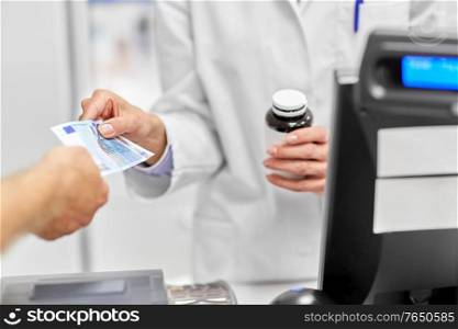 medicine, pharmaceutics, health care and people concept - close up of pharmacist selling drug and taking money at pharmacy. close up of pharmacist selling drug at pharmacy
