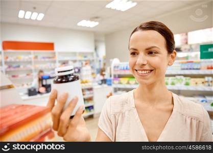 medicine, pharmaceutics, health care and people concept - happy female customer with drug jar at pharmacy