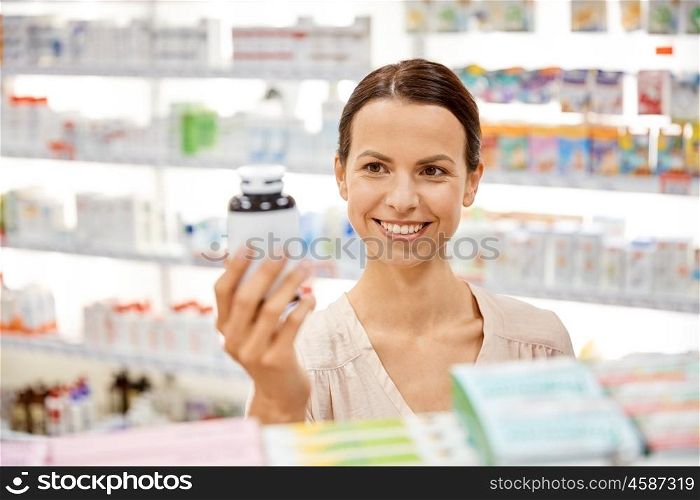 medicine, pharmaceutics, health care and people concept - happy female customer with drug jar at pharmacy. happy female customer with drug jar at pharmacy