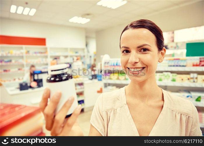 medicine, pharmaceutics, health care and people concept - happy female customer with drug jar at pharmacy