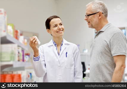 medicine, pharmaceutics, health care and people concept - happy pharmacist showing drug to senior man customer at drugstore