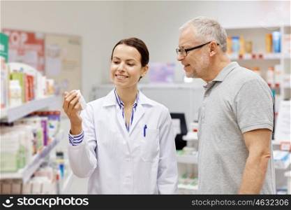 medicine, pharmaceutics, health care and people concept - happy pharmacist showing drug to senior man customer at drugstore