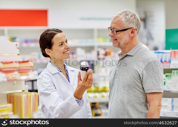 medicine, pharmaceutics, health care and people concept - happy pharmacist showing drug to senior man customer at drugstore