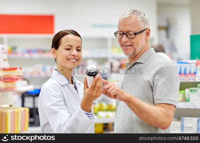 medicine, pharmaceutics, health care and people concept - happy pharmacist showing drug to senior man customer at drugstore