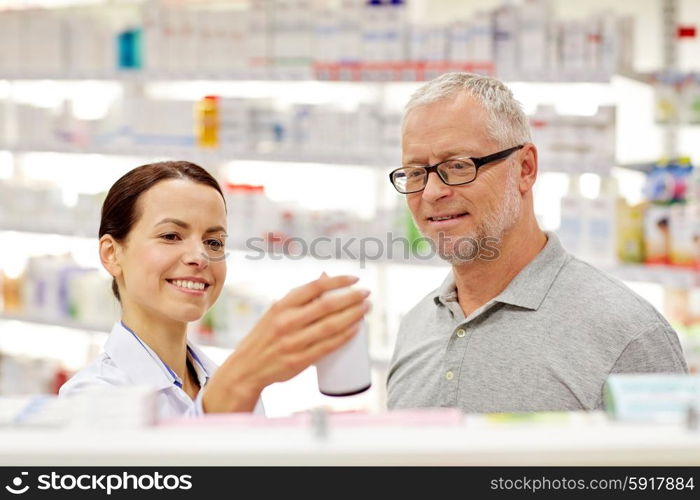 medicine, pharmaceutics, health care and people concept - happy pharmacist showing drug to senior man customer at drugstore