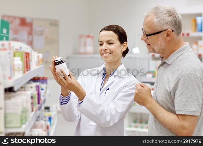 medicine, pharmaceutics, health care and people concept - happy pharmacist showing drug to senior man customer at drugstore