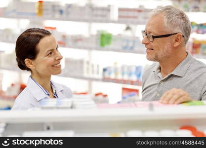 medicine, pharmaceutics, health care and people concept - happy pharmacist talking to senior man customer at drugstore