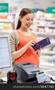 medicine, pharmaceutics, health care and people concept - happy pregnant woman with wallet in at cashbox drugstore