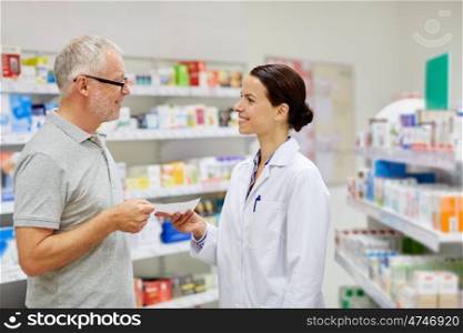 medicine, pharmaceutics, health care and people concept - happy senior man giving prescription to pharmacist at drugstore