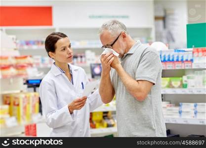 medicine, pharmaceutics, health care and people concept - pharmacist and sick senior man with flu blowing nose at pharmacy