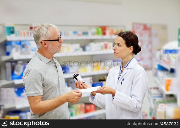 medicine, pharmaceutics, health care and people concept - pharmacist giving drug to senior man customer and taking prescription at drugstore