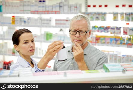 medicine, pharmaceutics, health care and people concept - pharmacist showing drug to senior man customer at drugstore