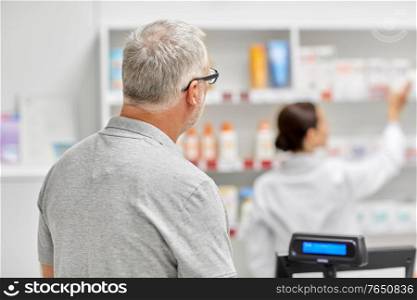 medicine, pharmaceutics, health care and people concept - senior man buying drug at pharmacy. senior man buying medicine at pharmacy
