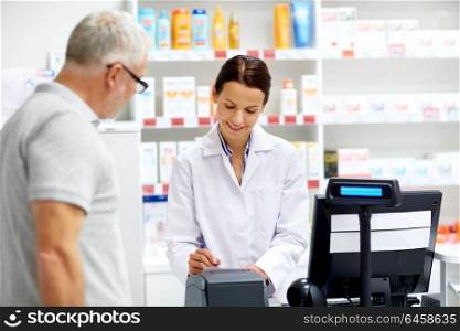 medicine, pharmaceutics, healthcare and people concept - apothecary writing prescription for senior male customer at drugstore. apothecary and senior customer at pharmacy