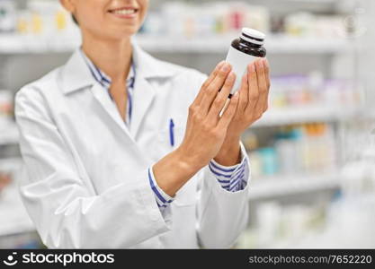 medicine, pharmaceutics, healthcare and people concept - close up of female pharmacist with drug at pharmacy. close up of pharmacist with medicine at pharmacy