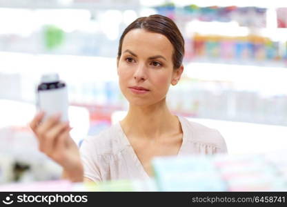 medicine, pharmaceutics, healthcare and people concept - female customer choosing drugs at pharmacy. female customer choosing drugs at pharmacy