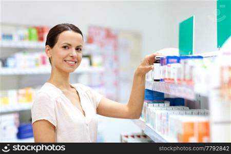 medicine, pharmaceutics, healthcare and people concept - female customer choosing drugs at pharmacy. female customer choosing drugs at pharmacy