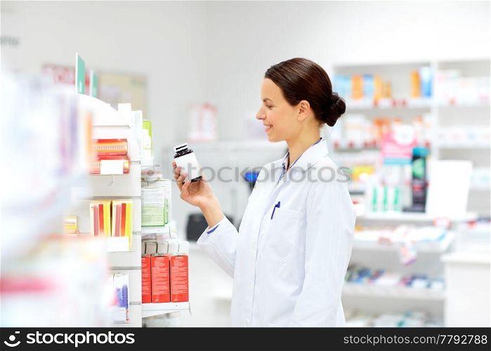 medicine, pharmaceutics, healthcare and people concept - happy female apothecary with drug at pharmacy. happy female apothecary with drug at pharmacy
