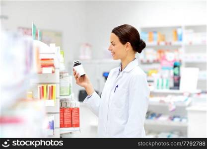 medicine, pharmaceutics, healthcare and people concept - happy female apothecary with drug at pharmacy. happy female apothecary with drug at pharmacy