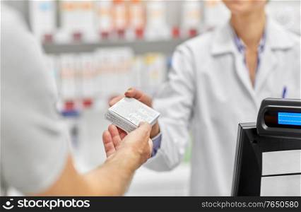 medicine, pharmaceutics, healthcare and people concept - pharmacist giving drug to senior male customer at drugstore. pharmacist and customer with medicine at pharmacy