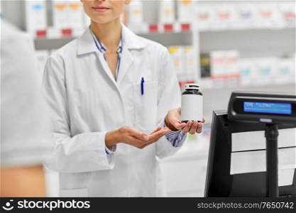 medicine, pharmaceutics, healthcare and people concept - pharmacist showing drug to customer at drugstore. pharmacist and customer with medicine at pharmacy