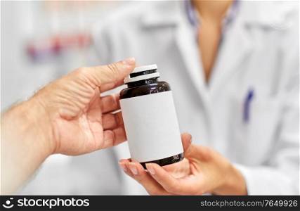 medicine, pharmaceutics, healthcare and people concept - pharmacist showing drug to male customer at drugstore. pharmacist and customer with medicine at pharmacy