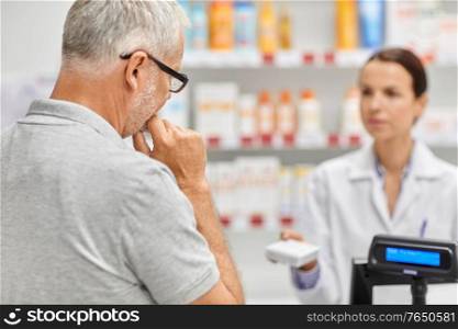 medicine, pharmaceutics, healthcare and people concept - pharmacist showing drug to senior man customer at drugstore. pharmacist and old man with medicine at pharmacy
